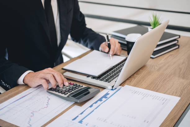istock Businessman working new project on laptop computer with report document and analyze, calculating financial data on graph documents, doing finance making notes statistics 1142661059