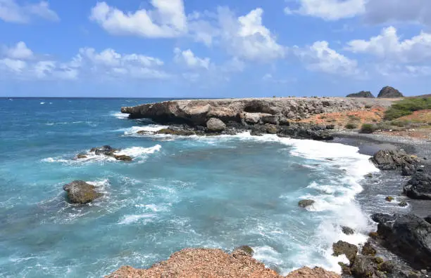The ocean swirling off the coast of Aruba's black sand stone beach.