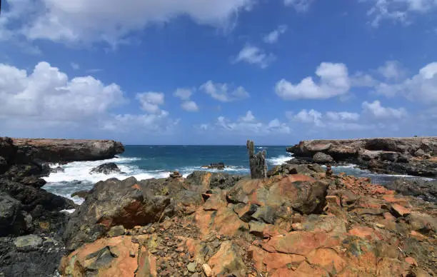 Rusty jagged rocks in front of Aruba's black sand beach.