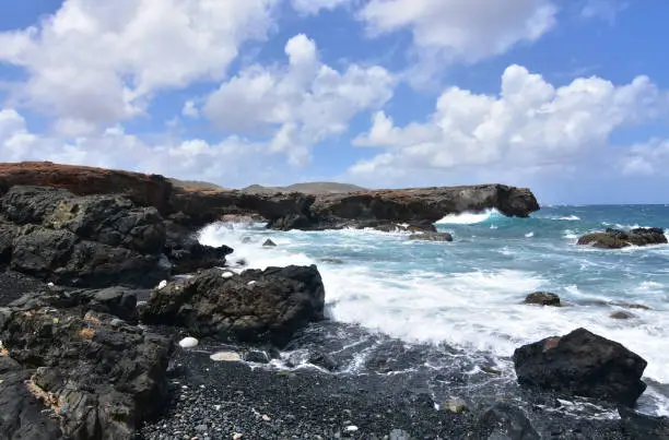 Waves crashing ashore on Aruba's black sand stone beach.