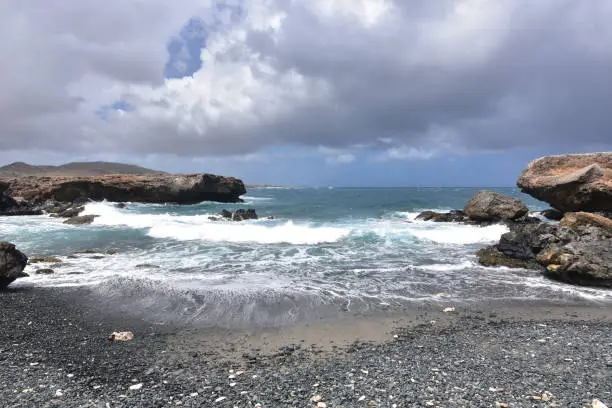 A stormy day over the black sand stone beach on the Carribean's island of Aruba.