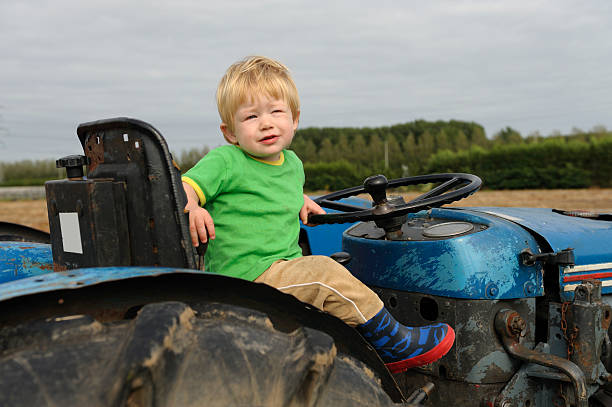 istock Little boy behind the wheels of a tractor 114266525