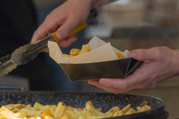 man serving chips into greaseproof paper and box