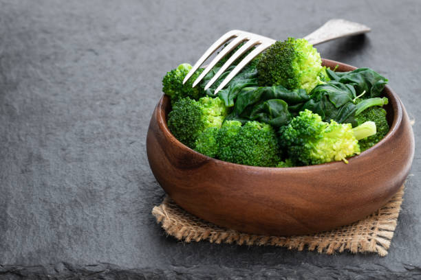 istock Steamed fresh broccoli with spinach on black stone background 1142672901