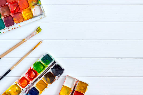 istock Old Paints and brushes on a white wooden background 1142673228