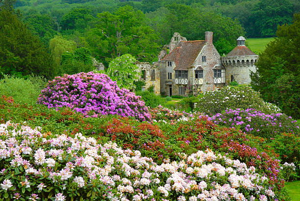 Old English castle surrounded by plenty of trees and flowers stock photo