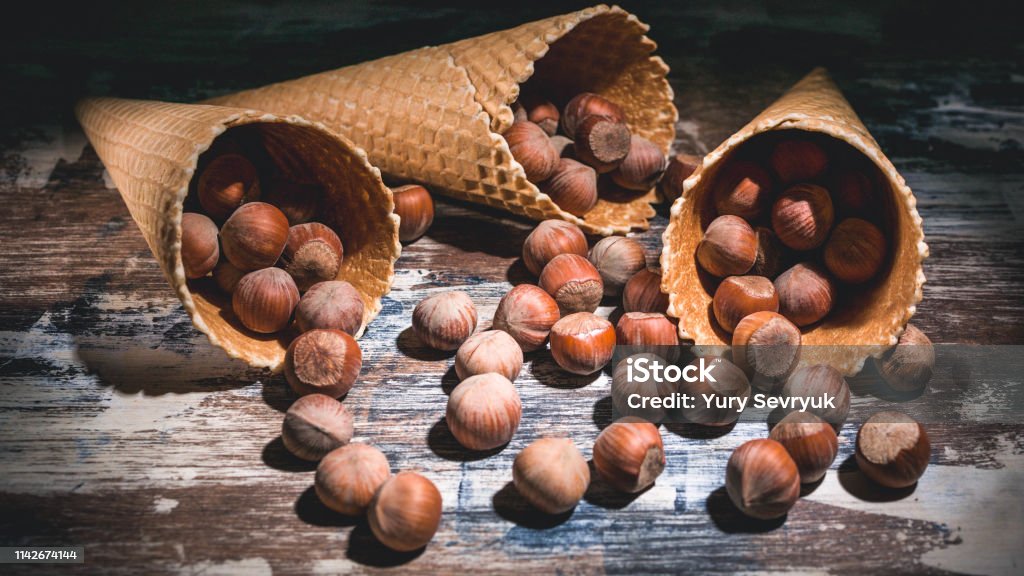 Hazelnut nuts in waffle cones on a dark background. Low key lighting. Almond Stock Photo