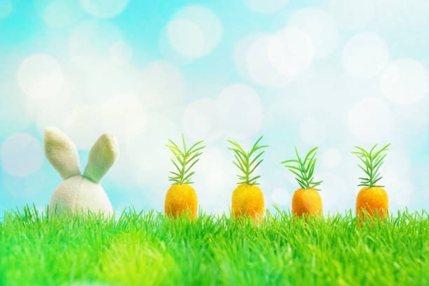 istock White rabbit doll with carrot on green grass. Spring holidays concept. 1142674609