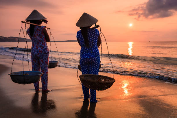 Vietnamese women carrying fruits on the beach, Vietnam Vietnamese women carrying fruits on the beach, South Vietnam ao dai stock pictures, royalty-free photos & images