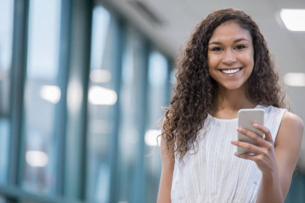 istock Young businesswoman or student smiles while texting in corridor 1142676358