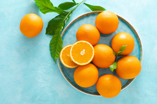 istock Oranges with leaves on blue background, top view 1142676381