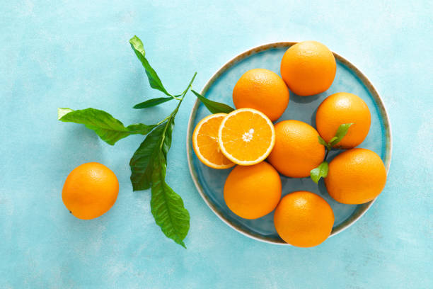 istock Oranges with leaves on blue background, top view 1142676387