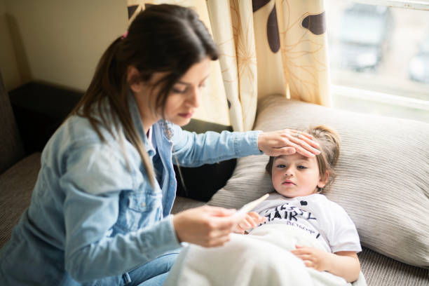 Mother checking on sick daughter laying in bed Mother checking temperature on sick daughter laying in bed offspring stock pictures, royalty-free photos & images