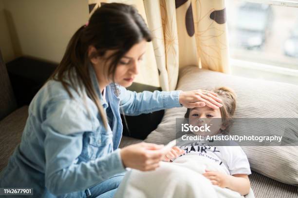 Mother Checking On Sick Daughter Laying In Bed Stock Photo - Download Image Now - Child, Illness, Fever