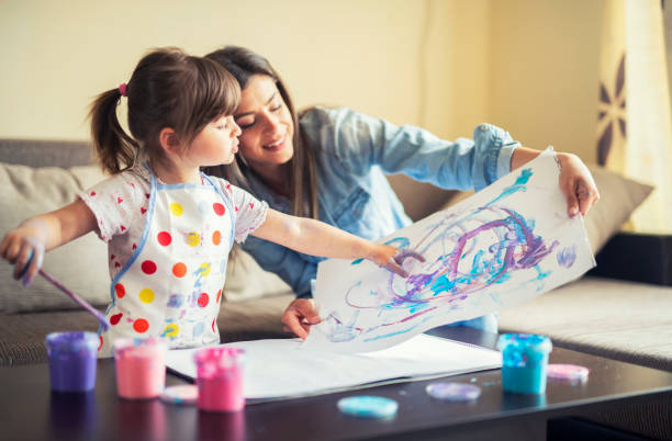 schattige kleine meisje schilderen met mama samen thuis, portret van moeder en dochter schilderij thuis - beroep schilder vrouw stockfoto's en -beelden