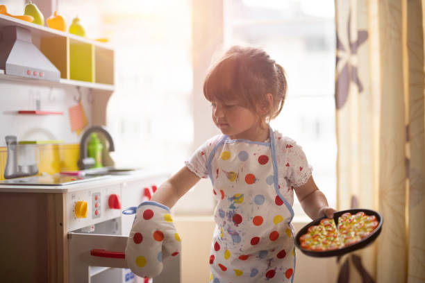 Little girl cooking on decorative kitchen at home.