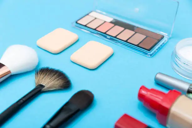Photo of Decorative cosmetics, makeup products and brushes on blue background