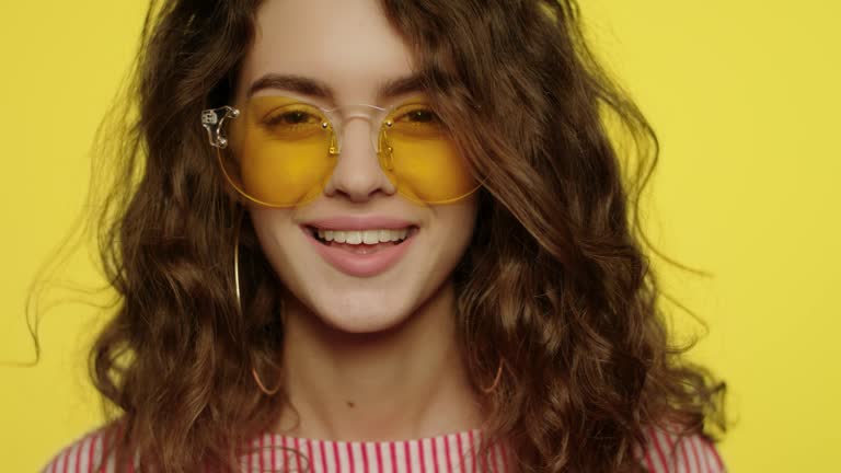 Young woman smiling on yellow background. Portrait of happy girl smiling