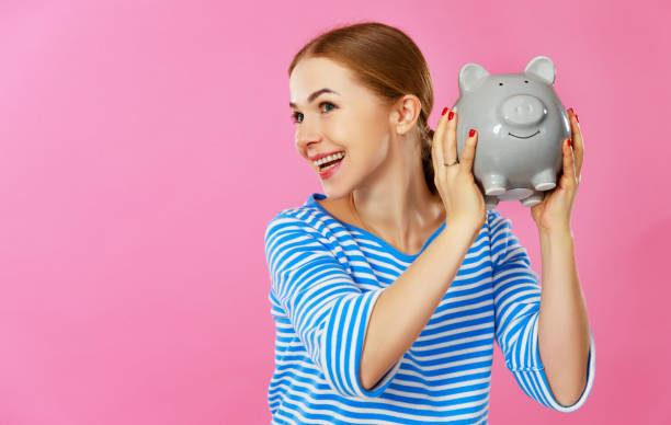 счастливая женщина с копилкой деньги на розовом фоне. концепция финансового планирования - beautiful pink business finance стоковые фото и изображения