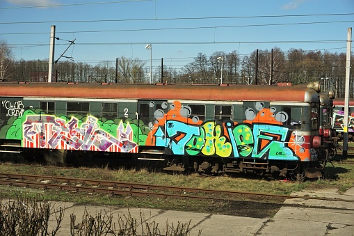Torun, Poland- March 27, 2019: Old rusting trains from the communist era sit on sidinsg outside Torun. These ones have been decorated with colorful graffiti.