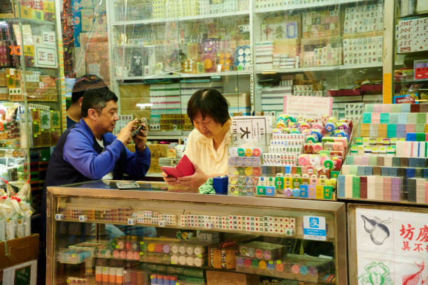 Hong Kong, April 13, 2019: a woman and two men at a street shop selling chinese mahjong, dice games and other traditional chinese board games. Mong Kok district.