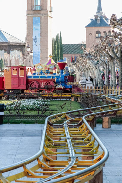 attraction train on cervantes square in the city of alcala de henares circuit of an attraction train with a locomotive red and blue color in the background in cervantes square in the city of alcala de henares, spain alcala de henares stock pictures, royalty-free photos & images