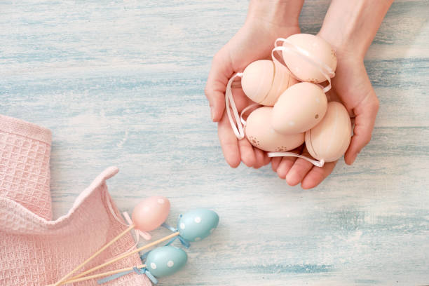 istock Easter flat lay in pastel colors. Easter eggs in female hands on light blue textured background 1142697776