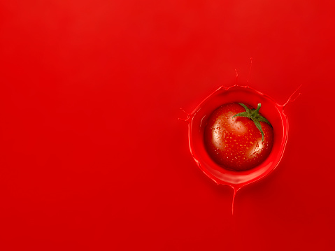Single Cherry tomato splashing into Tomato Juice