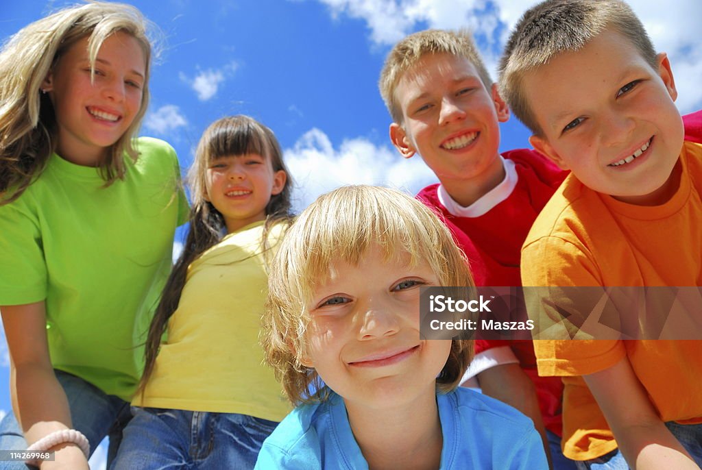 Five happy kids enjoying a sunny day outdoors A group of five happy kids with a blue sky behind them Beautiful People Stock Photo