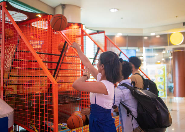Multi-Ethnic Asian friends playing basket ball in amusement arcade Multi-Ethnic Asian friends playing basket ball in amusement arcade arcade photos stock pictures, royalty-free photos & images