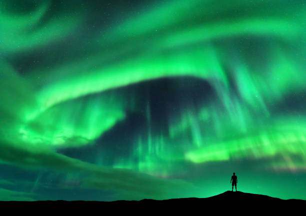 スタンディングマンのシルエットとオーロラ。ロフォーテン諸島、ノルウェー。オーロラと幸せな男。星と緑のポーラーライトと空。オーロラと人々との夜の風景。概念。旅行の背景 - norway lofoten nordic countries nordland county ストックフォトと画像