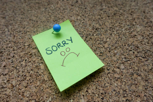 istock Green Sticky Note With Sorry Message And Blue Push Pin On Cork board 1142708787