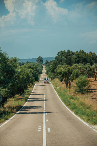 istock Road with lonely car through rural landscape and trees 1142712034