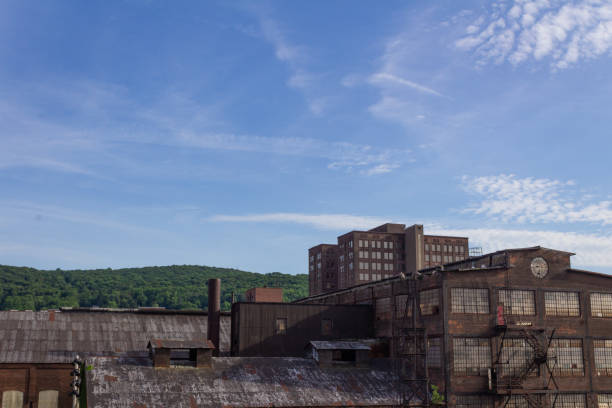 istock Derelict industrial warehouse with modern commercial building and forested hillside beyond 1142712862