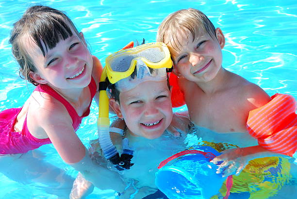 istock Three smiling kids in a swimming pool with toys 114271763