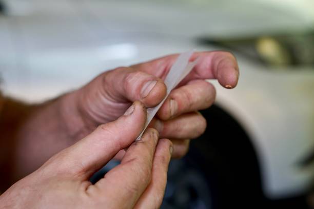 Close up of hands rolling a joint in front of a car. Concept of impaired driving stock photo