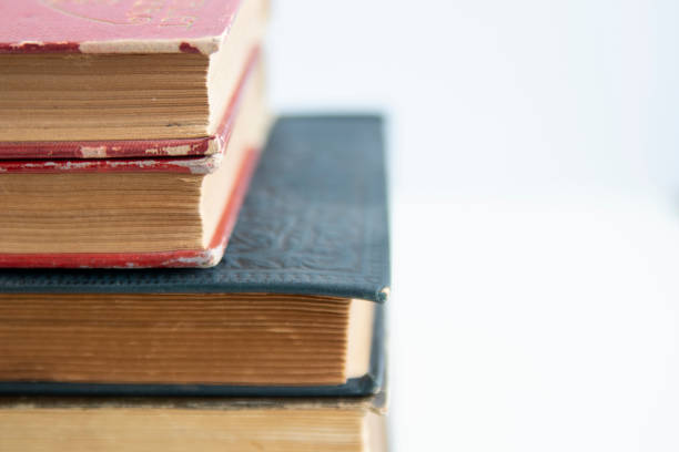 istock Old worn books stacked on white surface close up with copy space 1142720225