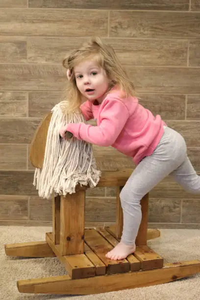 Toddler Girl Child on hand made wooden rocking horse with mop mane