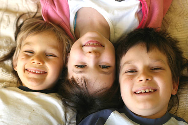 istock Three smiling children laying with their heads together 114273315