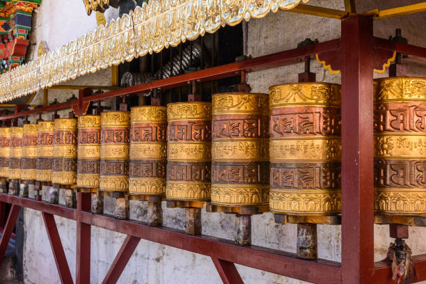 rodas de oração no templo de jokhang. os personagens (na língua newari e tibetano) sobre as rodas são os mantras "om mani padme hum", cada palavra significa "sagrado, talão, flor de lótus, espírito de iluminação" - tibetan script fotos - fotografias e filmes do acervo