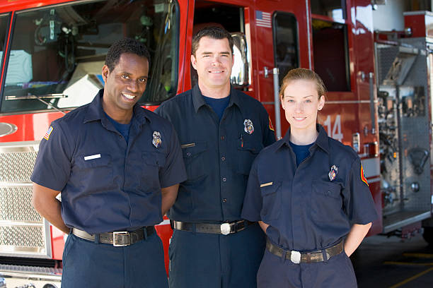 Portrait of firefighters standing by a fire engine
