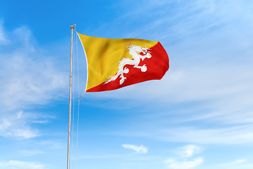 Bhutan flag blowing in the wind over nice blue sky background