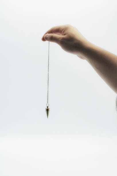 istock Pendulum dowsing on an isolated white background with a silver point. 1142748977