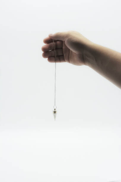 istock Pendulum dowsing on an isolated white background with a silver point. 1142748986