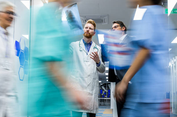 istock Young doctor and businessman cooperating while analyzing X-ray image in the hospital. 1142753672