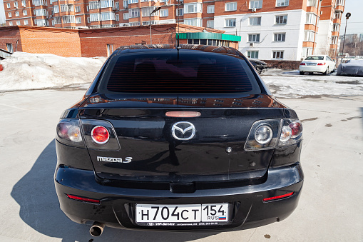Novosibirsk, Russia - 04.12.2019: Black Mazda 3 2008 year rear view with dark gray interior in excellent condition in a parking space among other cars