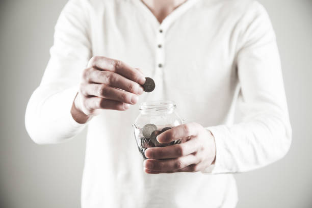 istock man hand holding coin with jar 1142758953