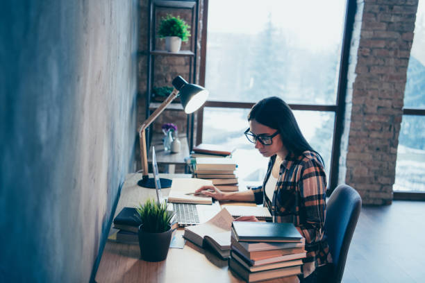 istock Profile side view of nice attractive smart clever intelligent genius creative brunette lady in checked shirt researching materials pile stack at industrial loft style interior work place station 1142764399