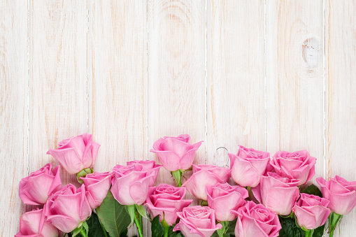 Pink roses over wooden table. Top view with copy space for your text
