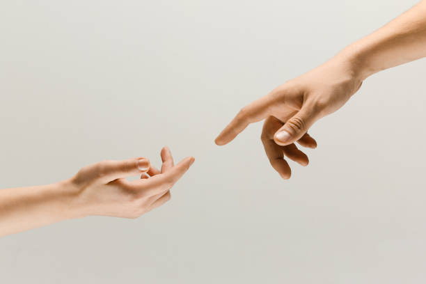 Two male hands trying to touch isolated on grey studio background Moment of weightless. Two male hands trying to touch like a creation of Adam sign isolated on grey studio background. Concept of human relation, community, togetherness, symbolism, culture and history. stroking stock pictures, royalty-free photos & images